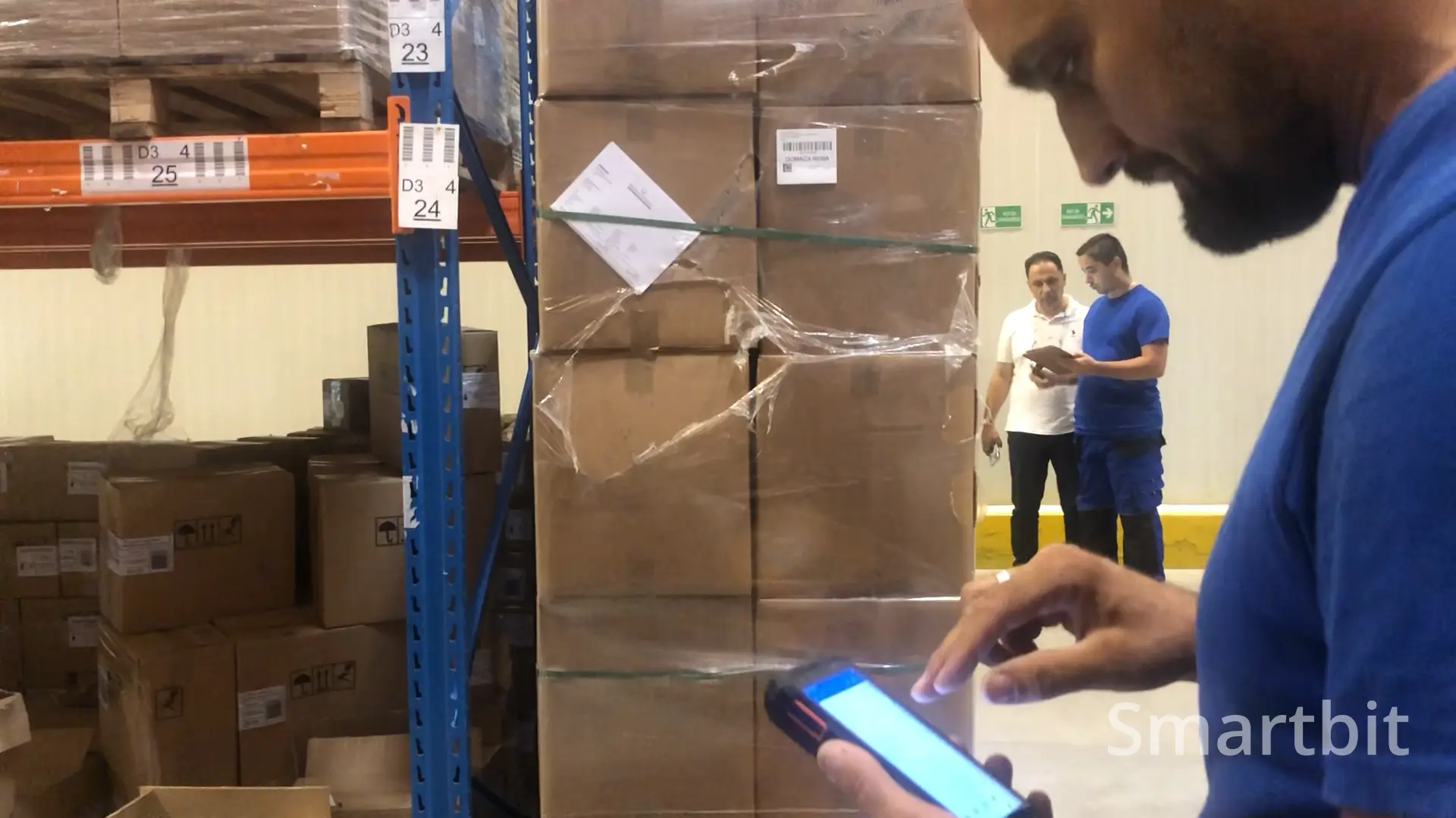 piker u skladištu sa mobilnim uređajem gleda u ekran
